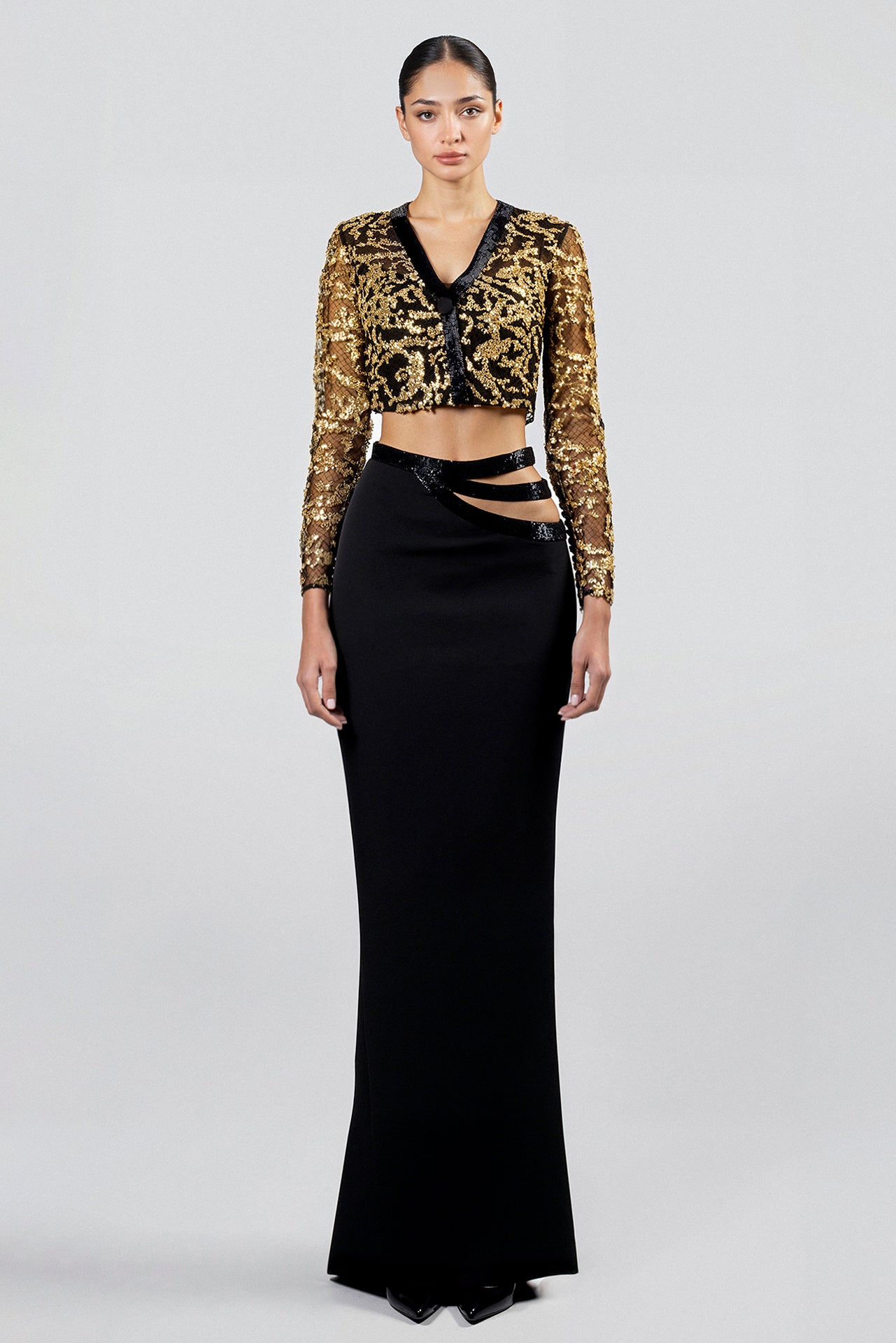 Load and play video in Gallery viewer, Gold silene embroidered mesh crop top, long sleeves, V-neckline, paired with black crepe maxi skirt, embroidered cutout waist details.