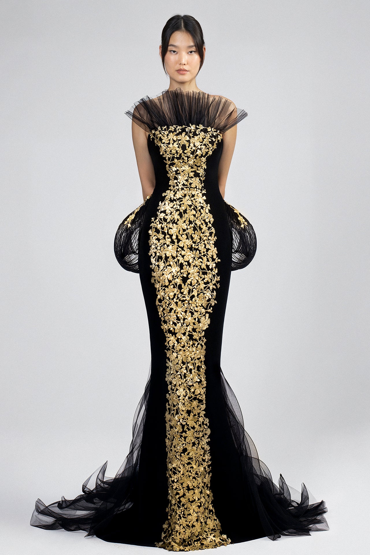 Load and play video in Gallery viewer, Black floor-length crepe gown, strapless bodice, gold embroidered lace panel, tulle neckline and cap sleeves, structured hip panels, mermaid silhouette, black tulle train with gold floral embroidery at waist.