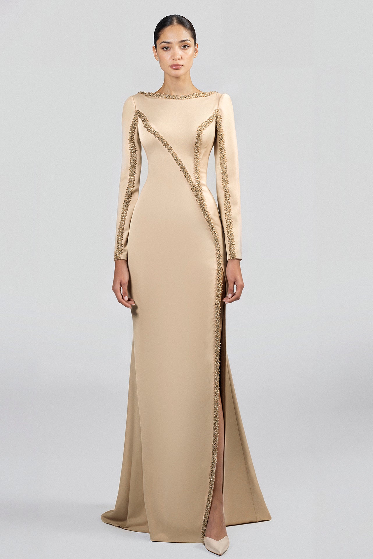 Load and play video in Gallery viewer, Champagne floor-length crepe dress, boat neckline, long sleeves, fitted silhouette, mermaid skirt with slit, low back, hand-embroidered embellishments on neckline, bodice, and skirt